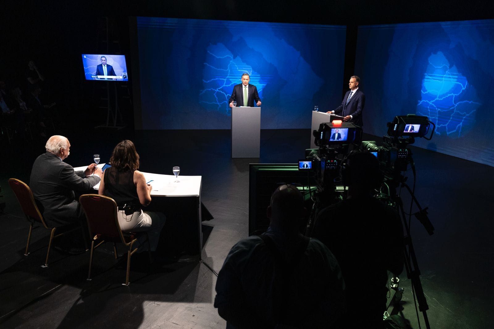 Vista general del set del debate: los dos candidatos en sus atriles frente a las pantallas, los moderadores en la mesa, las cámaras y un monitor de retorno
