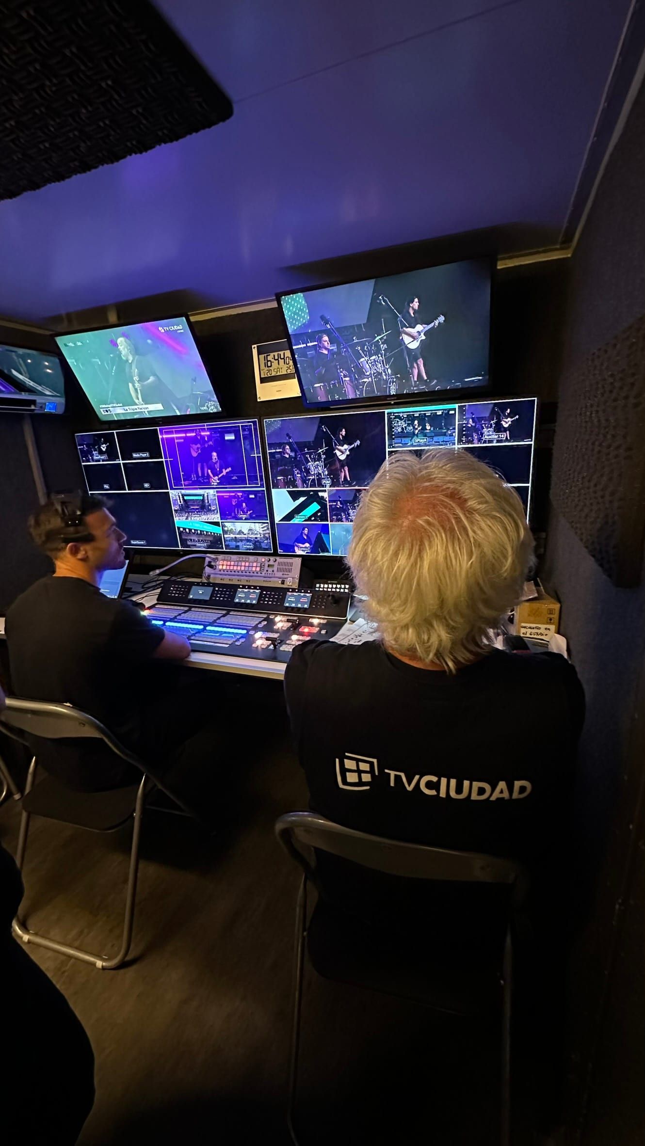 Dos realizadores en el control de la unidad móvil de TV Ciudad frente a la pared de monitores.