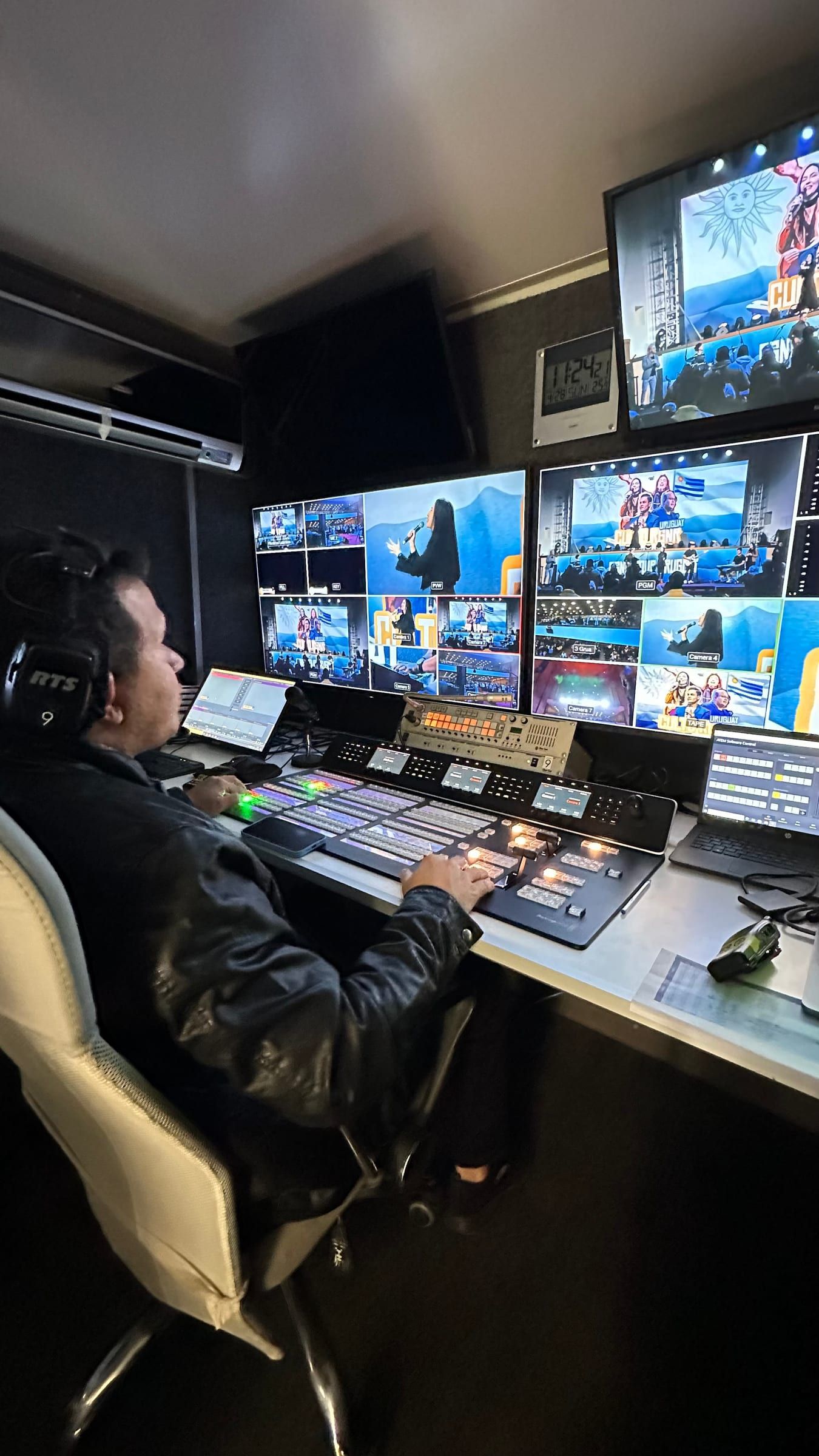 Realizador con auriculares operando el mezclador de video frente a las pantallas de la unidad móvil