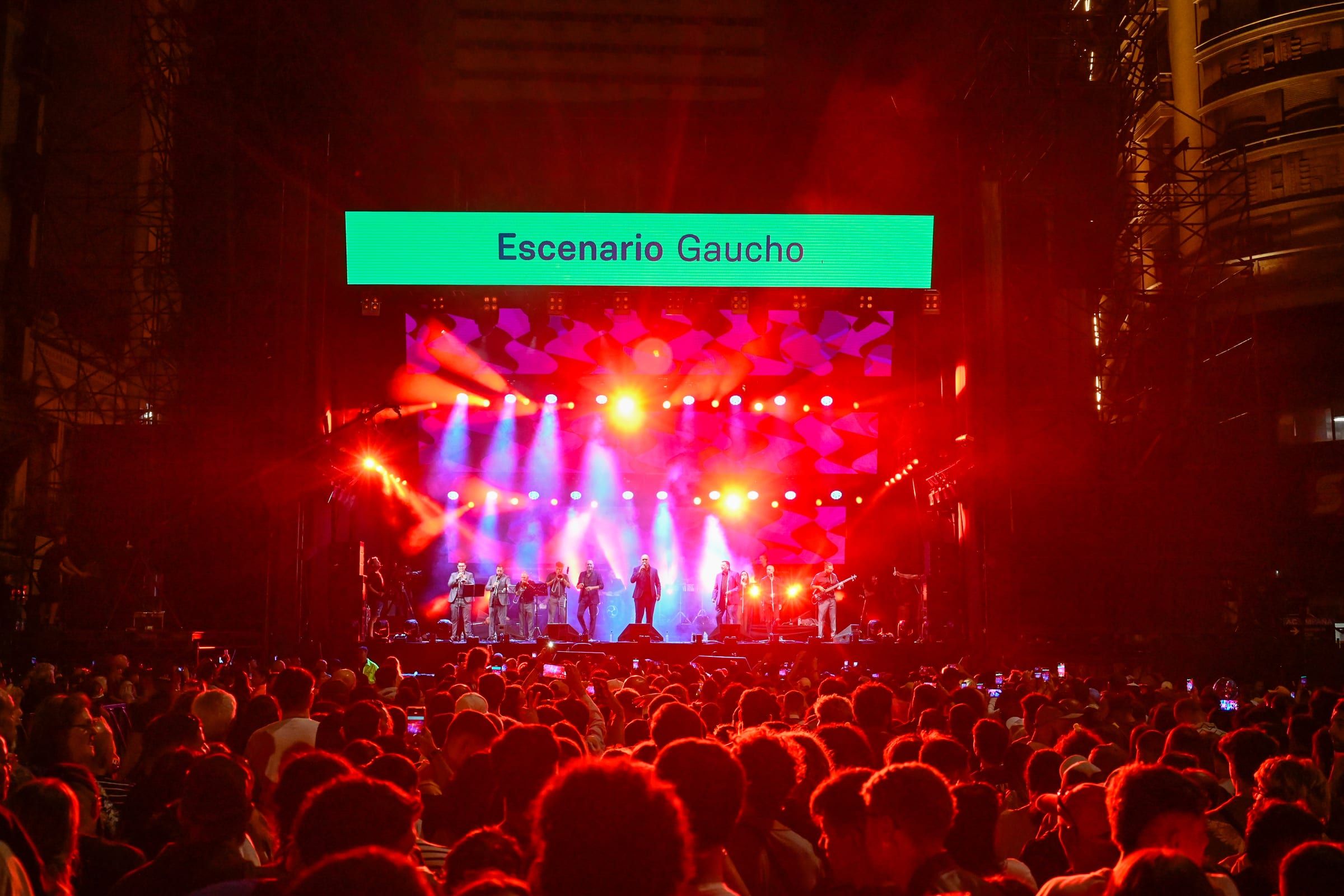 Escenario Gaucho iluminado en rojo, con el público frente a él, durante los festejos por los 300 años de Montevideo.