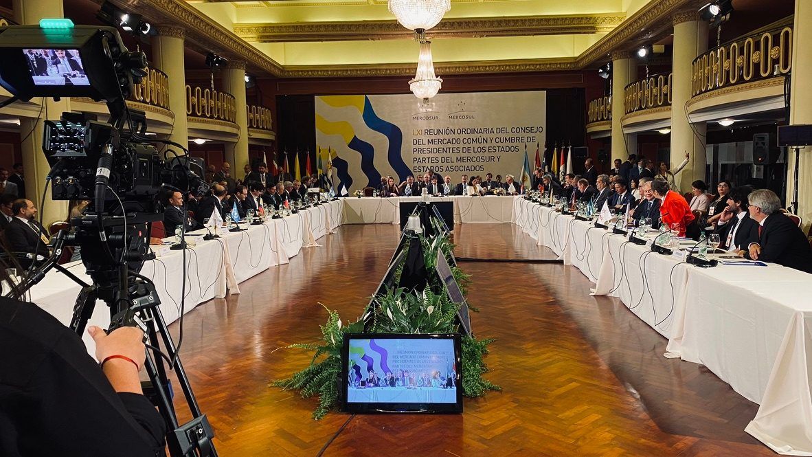 Cámara de transmisión en primer plano con la mesa de la LXI reunión del Consejo del Mercado Común al fondo.