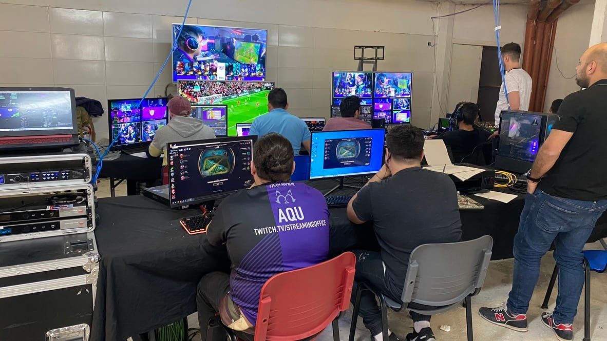 Puesto de transmisión para streaming de Gamecon 2022, con equipo de video, notebooks y monitores, y el equipo técnico trabajando