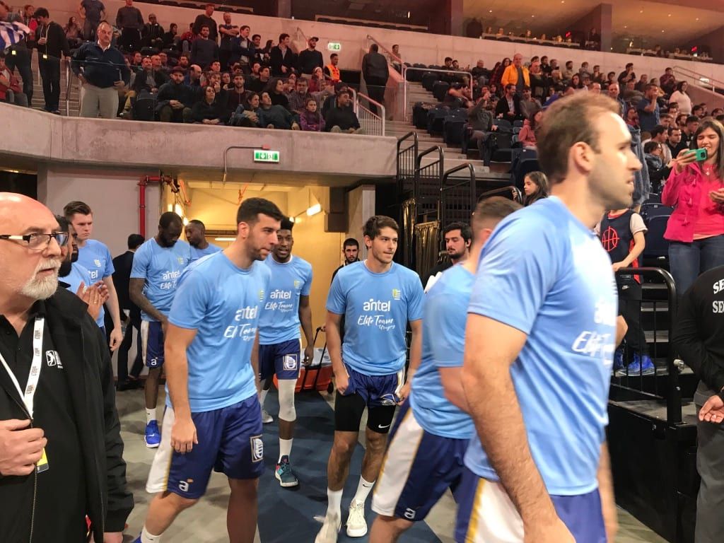 Jugadores con camisetas celestes de Antel salen al túnel antes de un partido