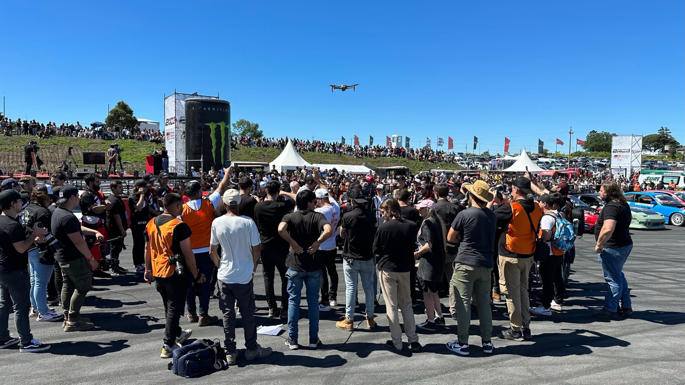 Público reunido en la pista del evento de drifting, con un dron en el aire y la torre de Monster Energy al fondo