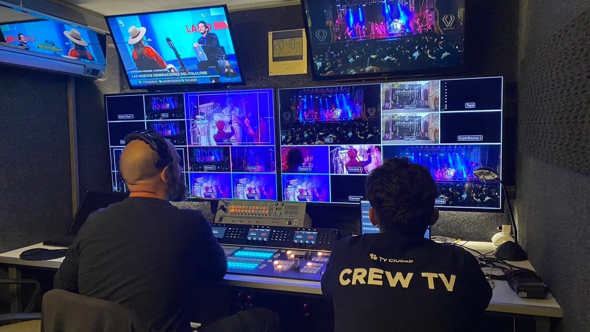 Dos operadores en el control de la unidad móvil frente a la pared de monitores con las cámaras del festival